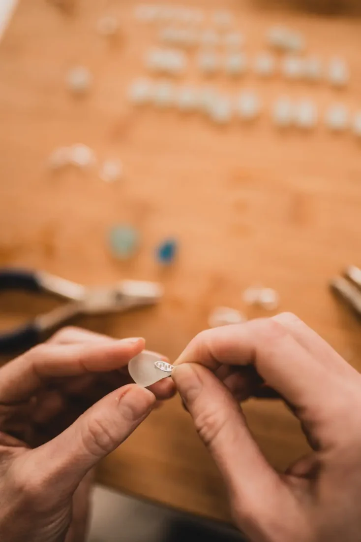 Violine fitting a silver finding to a frosted sea glass pendant by hand
